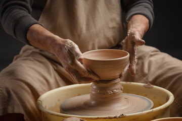 Hands of a potter, creating a ceramic pot on the pottery wheel