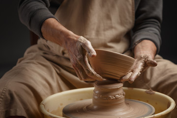Hands of a potter, creating a ceramic pot on the pottery wheel