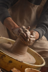 Hands of a potter, creating a ceramic pot on the pottery wheel