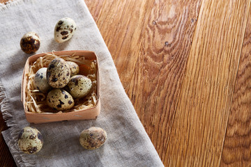Quail eggs in the container over rustic wooden table, close-up, high angle view, selective focus.
