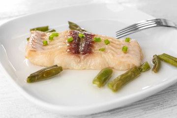 Plate with tasty fish and green beans on table