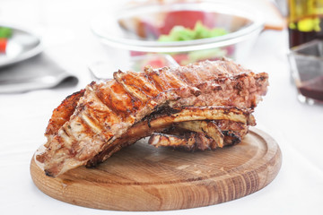 Delicious juicy ribs on wooden board