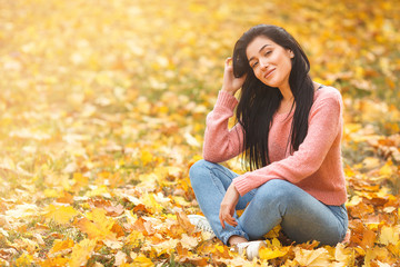 Very beautiful young woman on the autumn background. Close up portrait of smiling young pretty girl in the fall time.