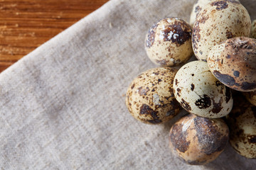 Obraz premium Quail eggs arranged in pyramid on a napkin over a wooden table, close-up, selective focus.