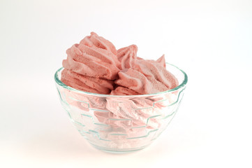 Marshmallow in pink color in a glass plate on a white background.