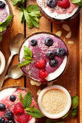 Blueberry smoothie in a coconut bowl with fresh blueberries and raspberries, mint, chia seeds and sesame seeds. Healthy and delicious dessert or breakfast, vegetarian food
