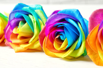 Fototapeta na wymiar Amazing rainbow rose flowers on table, closeup