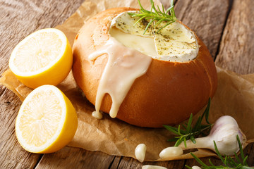 Rustic fondue in bread with melted camembert cheese close-up on the table. horizontal