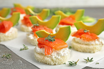 Tasty sandwiches with fresh sliced salmon fillet and avocado on table, closeup
