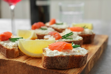 Sandwiches with fresh sliced salmon fillet on wooden board, closeup