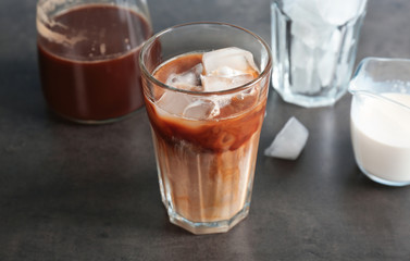 Glass with cold brew coffee and milk on table