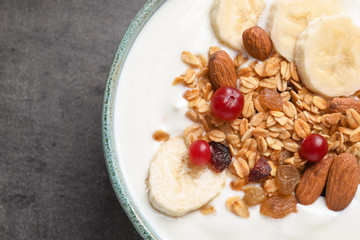 Bowl with yogurt, banana and granola on table, top view