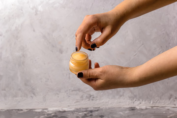 female hands holding cosmetic product in a glass jar