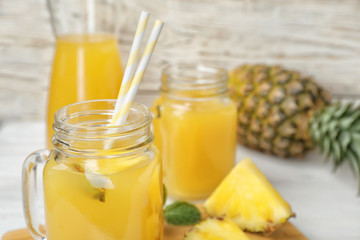 Mason jars with delicious pineapple juice on table