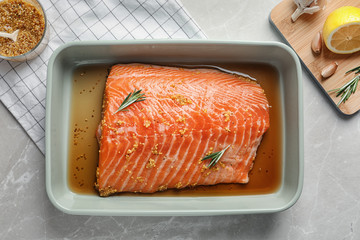 Marinated salmon fillet in dish on table, top view