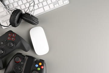 Gamepads, mouse and headphones on gray background