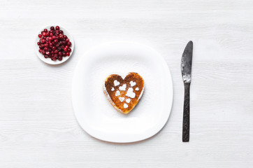 Freshly baked heart shape curd on the plate with cranberry and powdered sugar on white wooden table background.
