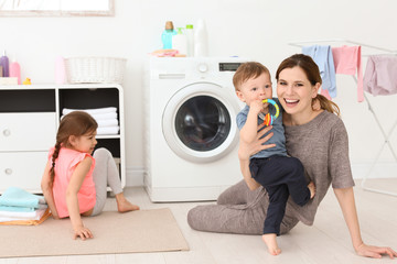 Housewife with little children in laundry room