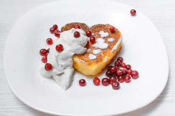 Freshly baked curd on the plate with cranberry and powdered sugar and sour cream on white wooden table background.