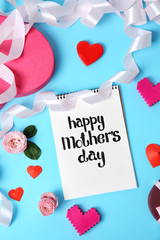Notebook with phrase "HAPPY MOTHER'S DAY" and decor on color background