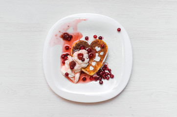 Freshly baked curd on the plate with cranberry and powdered sugar and sour cream on white wooden table background.