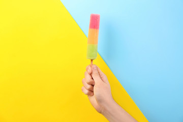Man holding yummy ice cream on color background. Focus on hand
