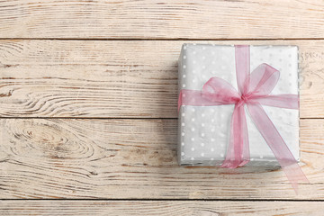 Elegant gift box with bow on wooden background, top view