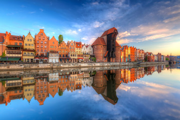 Fototapeta premium Piękne stare miasto w Gdańsku odzwierciedlone w Motławie o wschodzie słońca, Polska.