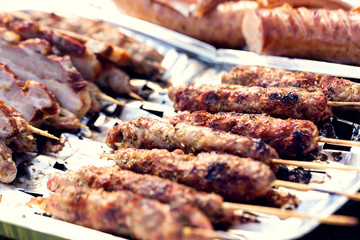 Grilled meat on sticks, sausage and bacon. Family picnic in the open air. Shallow depth of field.