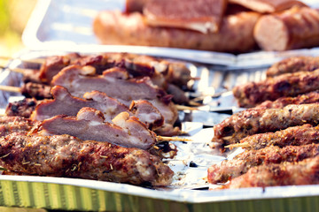 Grilled meat on sticks, sausage and bacon. Family picnic in the open air. Shallow depth of field.