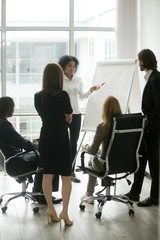 Black female team leader teaching diverse business people at meeting, multiracial executive group...