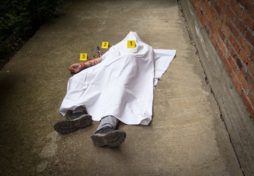 A dead man covered with white sheets. A bloody knife in the background