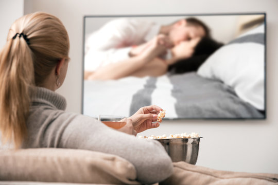 Young Woman With Popcorn And Juice Is Watching A Romantic Movie On A Big Modern  TV