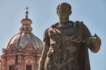 Rome, Bronze statue of emperor Julius Caesar, in the background the dome of  Saints Luca and Martina Church