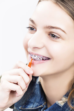 Dental Health Ideas and Concepts.Smiling Caucasian Female Teenager With Teeth Braces. Cleaning Brackets Using Bristle Brush.