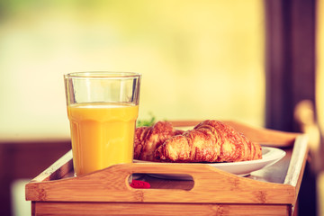 Breakfast on little table, orange juice croissant