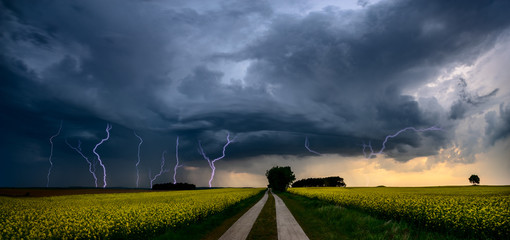 approaching storm over a country road - obrazy, fototapety, plakaty