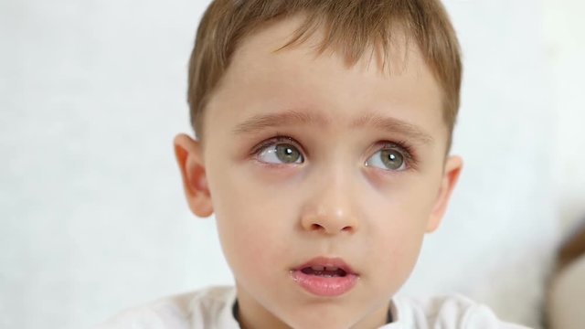Portrait of a baby boy. The boy's face expresses indifference, neutral emotions, in slow motion, close-up.