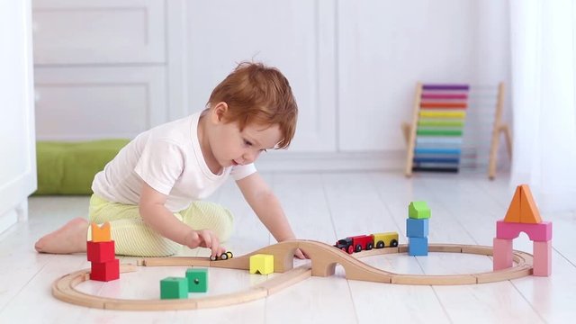 cute toddler boy playing the toy train and railroad at home