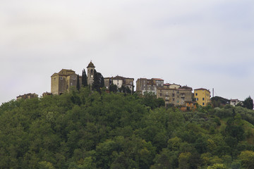Fototapeta premium Italian village in Tuscany with city walls and towers on a wooded hill near Pisa