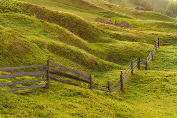 Fototapeta na wymiar Wooden fence on a green meadow