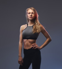 Sexy slim blonde girl in a sportswear posing in a studio.