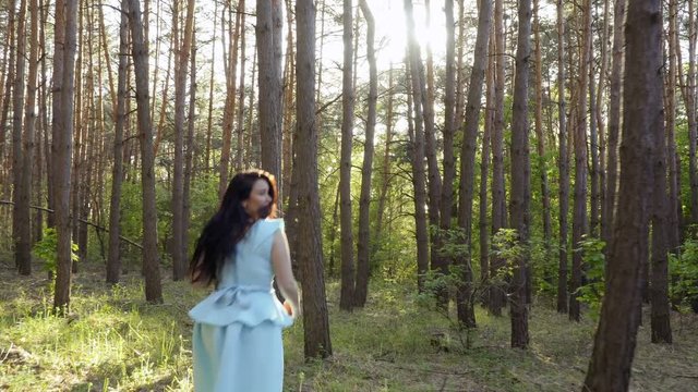 Beautiful girl wearing blue dress and holding apple, running in the forest