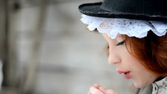 Portrait of a red-haired girl in ethnic clothes and in a hat with lace.