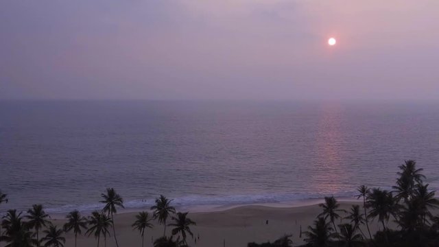 Tropical sunset. The sun sets over the ocean, the sea waves in the evening, tropical pams and ocean