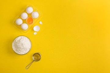 Baking flat lay background with eggs floor sieve on yellow