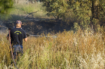 Firefighter fire extinguishing  field with dry grass