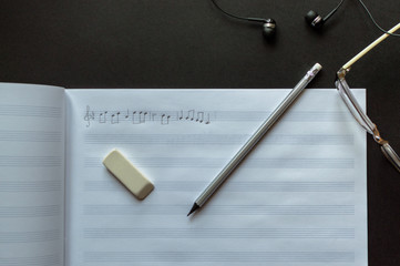 Top view of the pencil, eyeglasses and eraser laying near to the sheet notes with handwritten...
