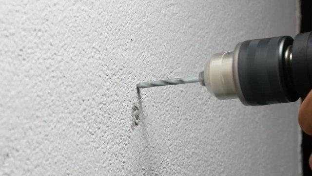 Close-up View of Spinning Metal Spiral electric Drill Bit on the concrete cement white wall