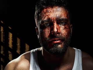 A strong, a serious, muscular man in a white t-shirt is worth and looks in camera. He's got the beard on the face and different emotions